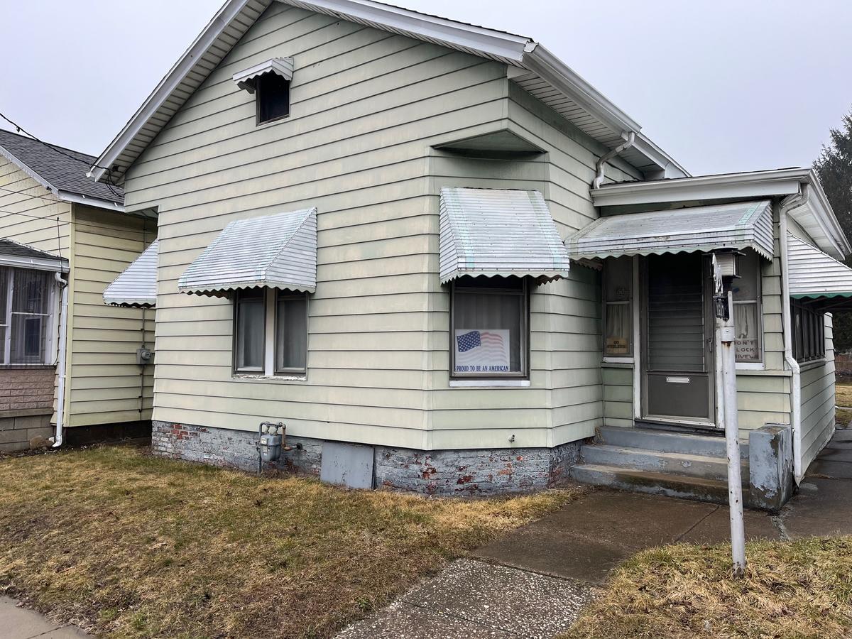 Erie PA 1920s bungalow — green siding, storm awnings, vacant