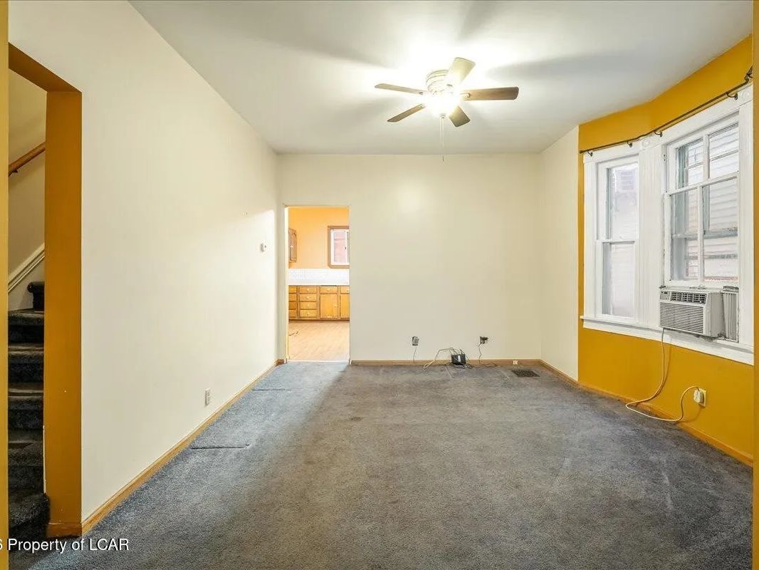 Living space with original trim and carpet in one unit of the Wilkes-Barre two-unit