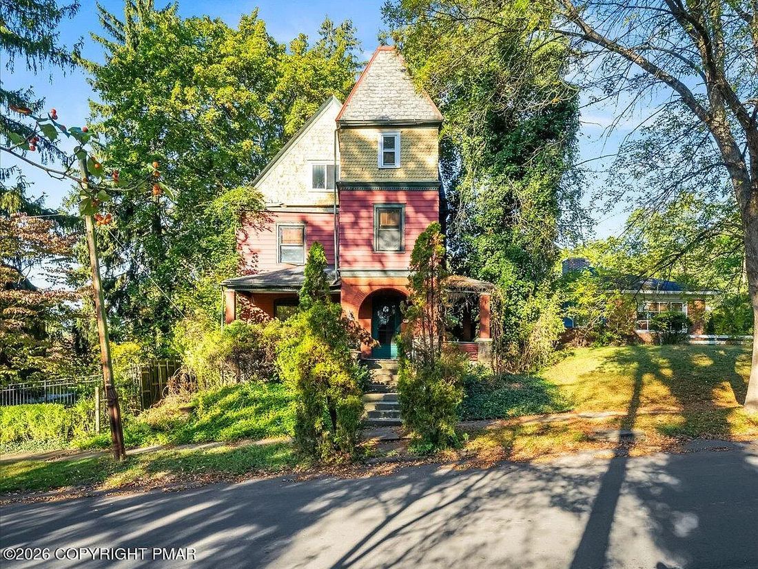 Street view of the distressed Williamsport Victorian and its overgrown frontage