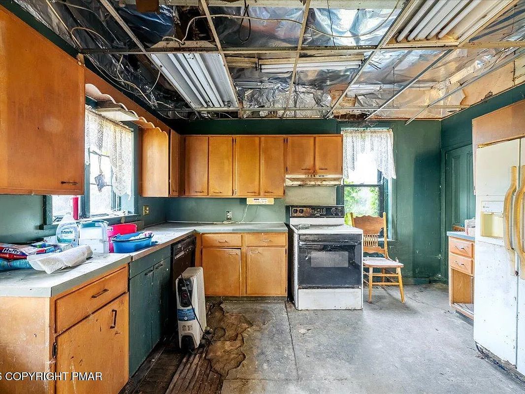Collapsed ceiling and exposed structure above the kitchen from long-term roof leaks