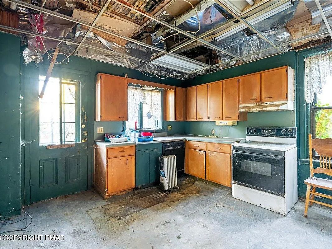Kitchen with dated cabinetry and damaged ceiling in the Williamsport, PA property