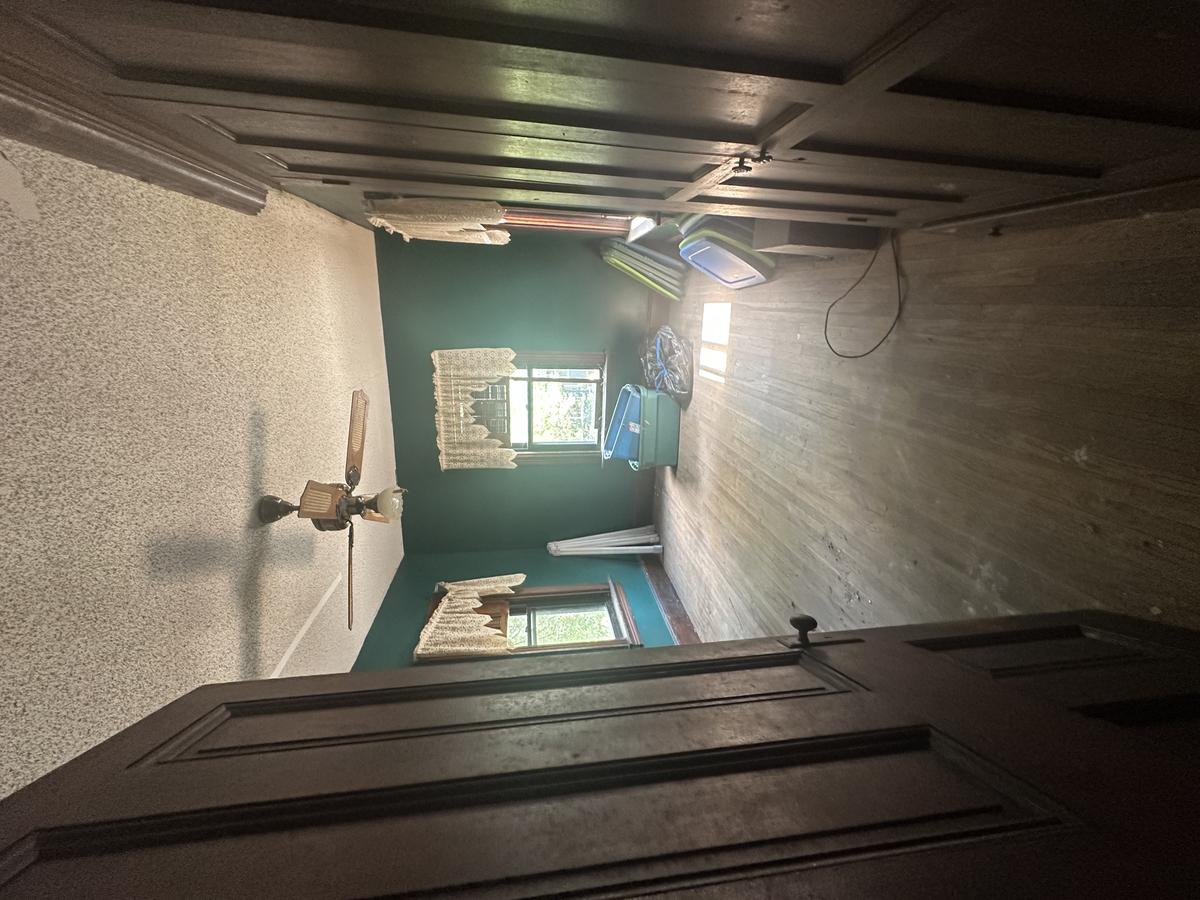 Victorian bedroom before — teal paint, original doors, lace curtains, hardwood floors