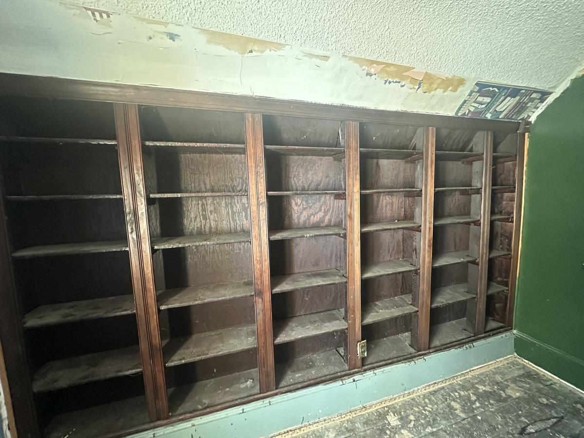 Victorian library before — floor-to-ceiling built-in bookshelves, water-damaged ceiling